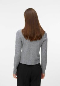 Grijze lange mouwen trui met een strakke pasvorm en geribbelde zoom, gecombineerd met zwarte broek. Focus op zachte textuur en minimalistische stijl.