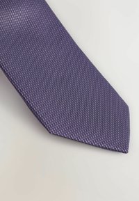 Cravat purpuriu cu un model texturat, având un vârf ascuțit și o strălucire subtilă. Țesătura pare netedă, cu un model în dantelă asemănător diamantului.