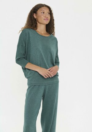 Grünes, leichtes Strickset bestehend aus einem locker sitzenden Oberteil mit weitem Halsausschnitt und gerippten 3/4-Ärmeln, kombiniert mit passenden schmal zulaufenden Hosen.