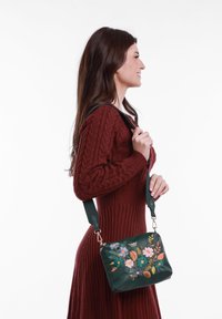 Zelená kožená kabelka s květinovou výšivkou, obdélníkový tvar, odnímatelný popruh a zlaté kovové detaily.