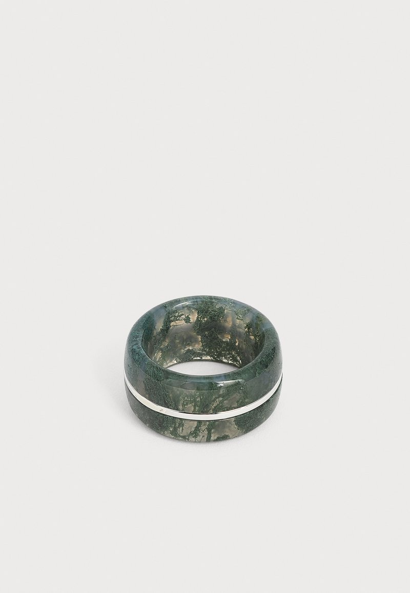 Bague épaisse en résine verte translucide avec des motifs sombres semblables à de la mousse et une fine bande argentée autour du milieu.