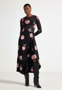 Abito nero con stampa di rose rosa; maniche lunghe; strato superiore trasparente; orlo asimmetrico; abbinato a stivali neri con tacco al ginocchio.