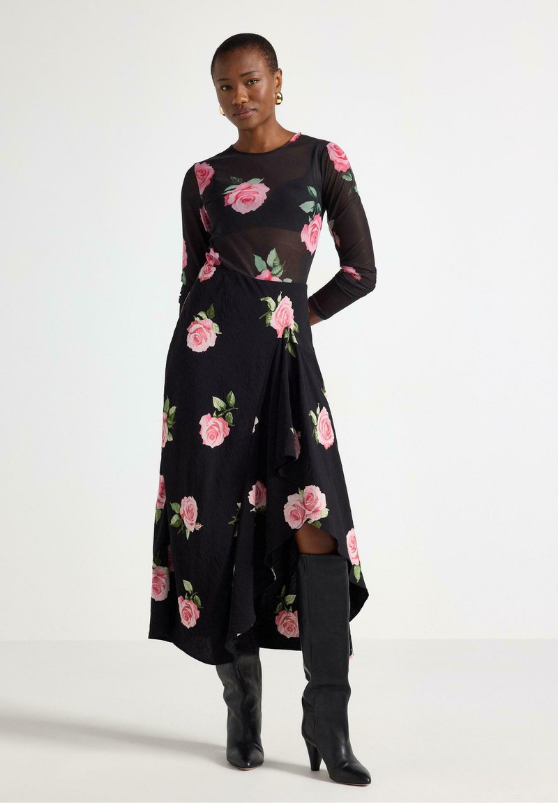 Abito nero con stampa di rose rosa; maniche lunghe; strato superiore trasparente; orlo asimmetrico; abbinato a stivali neri con tacco al ginocchio.