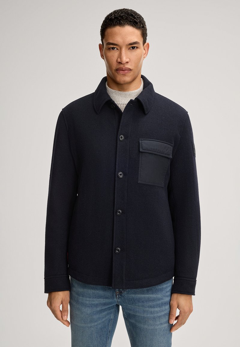 Veste chemise en mélange de laine bleu marine avec un col, fermeture à boutons sur le devant et une poche sur la poitrine à gauche avec un accent en tissu texturé.