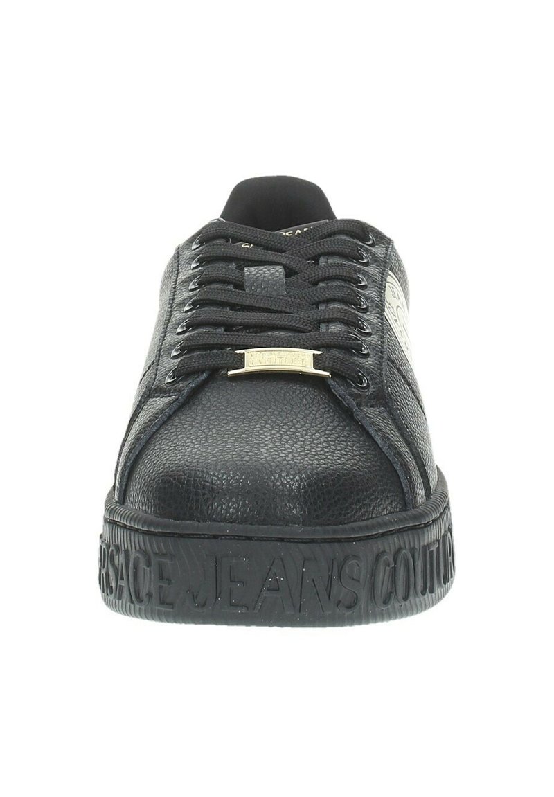 Baskets noires avec tige en cuir texturé, bout rond, lacets plats, logo embossé et semelle en caoutchouc à motifs.