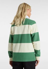 Groen en crèmekleurig gestreept langemouwen shirt met een ronde hals. Heeft een relaxte pasvorm en ribgebreide boorden. Gemaakt van zacht katoen.