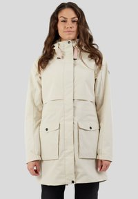Parka imperméable beige avec un col haut, une capuche ajustable, deux poches avant avec rabats et des fermetures à boutons-pression.