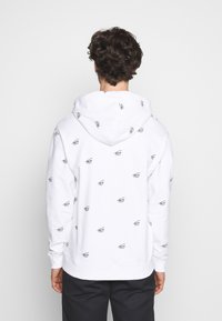 Felpa bianca con stampa del logo ripetuta in nero, caratterizzata da un cappuccio con coulisse, polsini a costine e una vestibilità regolare. Design semplice senza dettagli aggiuntivi.