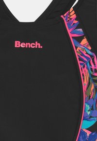 Zwarte zwempak met aan de ene kant een kleurrijk bloemenpatroon en op de borst staat prominent het roze logo "Bench."