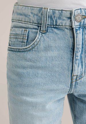 Jasnoniebieskie jeansy z denimu o wyblakłym wyglądzie, z pojedynczą tylną kieszenią, pomarańczowymi przeszyciami i metalowym zapięciem na guziki.