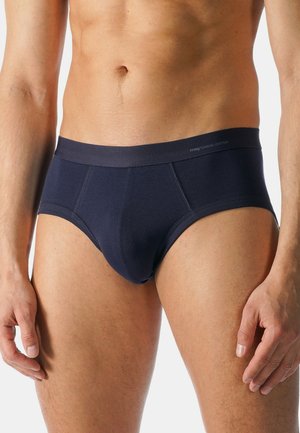 Marineblaue Baumwollslips mit enger Passform, flachem Bund und kontrastierenden Nähten. Glatte Textur und minimales Branding am Bund.