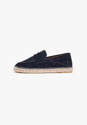 Zapato slip-on de ante azul marino con punta redonda y correa decorativa. Suela envuelta en yute con detalles de costura visibles.