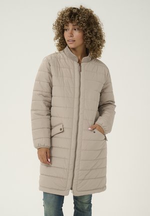 Beige quilted coat with a high collar, long sleeves, and two side pockets. Features a front zipper and a textured appearance.