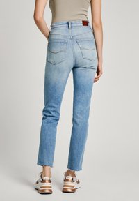 Ljusblå högmidjade jeans med en blekt design, som har fem fickor, lapplistad detalj och rå avslutning vid anklarna. Matchade med sneakers.