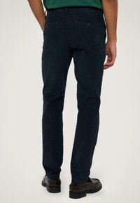 Tmavě námořnické kordové kalhoty se slim fit, které mají dvě zadní kapsy a plochý pas, doplněné hnědými koženými botami.