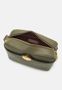 Borsa a tracolla in pelle verde oliva con hardware dorato, chiusura con zip e texture liscia. Interno foderato in tessuto scuro con etichetta del brand.
