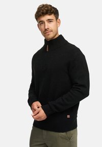 Zwarte zip-up sweater met hoge kraag, ribgebreide boorden en zoom. Bevat een kleine leren accent aan de onderkant links. Zachte textuur.