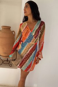 Spalvinga suknelė su horizontaliomis raudonos, mėlynos ir auksinės spalvų juostelėmis, ilgomis rankovėmis ir diržu juosmens srityje. Minkšta medžiaga ir sklandus dizainas.