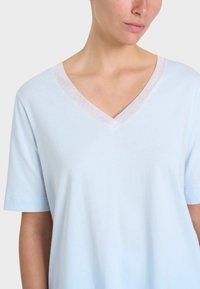 T-shirt azzurro chiaro a maniche corte con scollo a V, dotato di un bordo trasparente attorno al collo e una texture morbida e liscia.