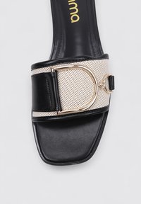 Sandalia deslizante negra y beige con una correa texturizada, detalle de hebilla dorada y diseño de punta cuadrada. Materiales de cuero suave y malla.