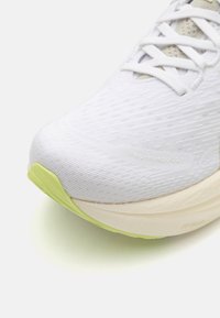 White running shoe featuring a textured upper, light yellow accent on the sole, and a cushioned midsole for support.