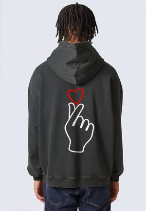 Felpa con cappuccio grigio scuro, con un grande ricamo bianco di una mano e un cuore rosso sul retro. Presenta un cappuccio con cordini e polsini a costine.