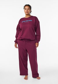 Burgundy sweat set featuring a crew neck and long sleeves, with a blue "DETOX YOUR MIND" text graphic. Loose-fit pants with a drawstring waist.