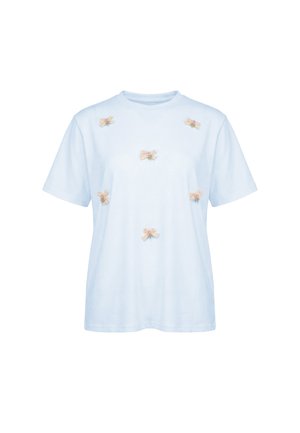 Lyseblå kortærmet t-shirt med seks små beige og lyserøde sløjfer jævnt fordelt på forsiden, vist på en ensfarvet hvid baggrund.