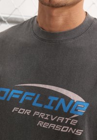 Grå bomulds t-shirt med blå og hvide tekst, der skriver "OFFLINE FOR PRIVATE REASONS," med rund halsudskæring og blød tekstur.