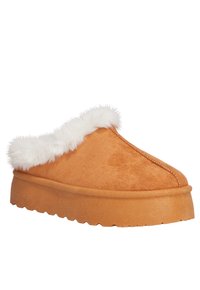 Zapatillas de ante en color beige con un suave forro de piel sintética blanca, punta redonda y suela de goma gruesa, con un detalle texturizado.