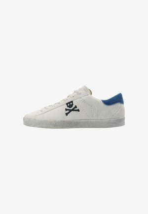 Zapatillas bajas de ante blanco con una pestaña en el talón azul. Cuentan con bordado de calavera y huesos cruzados en negro en el costado y suela texturizada en gris.