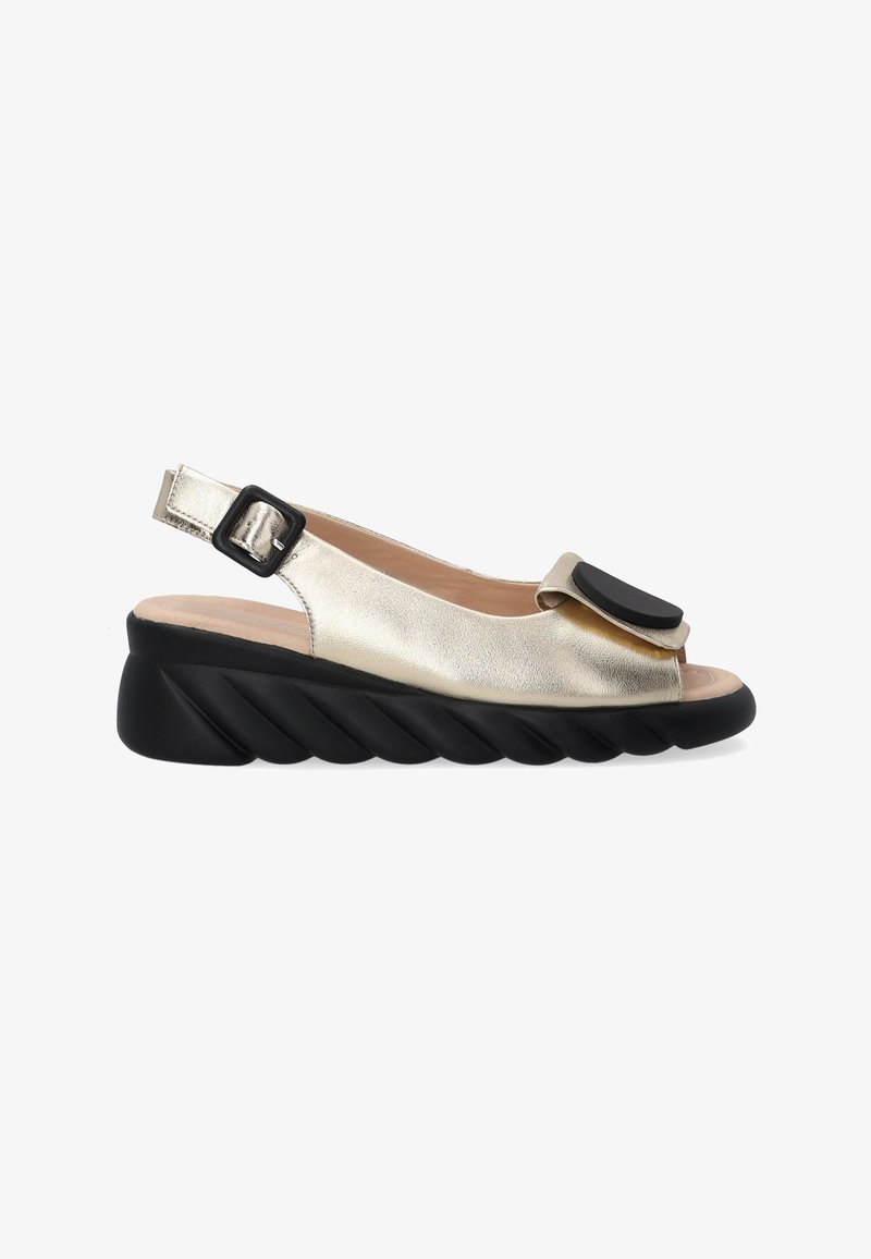 Sandale slingback dorée métallique avec un accent noir, design à bout ouvert et semelle compensée texturée. Boucle ajustable pour un ajustement sécurisé.