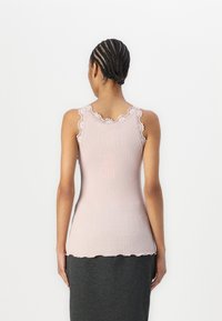 Rosa, gerippte Tanktop mit Spitzenbesatz an den Schulterträgern und gewelltem Saum, aus einem weichen, dehnbaren Material gefertigt.