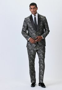 Black and gray floral-patterned suit with satin shawl lapels, tailored fit, paired with a tie and glossy black shoes.