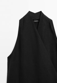 Zwarte mouwloze overslagvest met V-hals, gemaakt van gestructureerde stof, met het label "Massimo Dutti" aan de binnenkant van de hals.