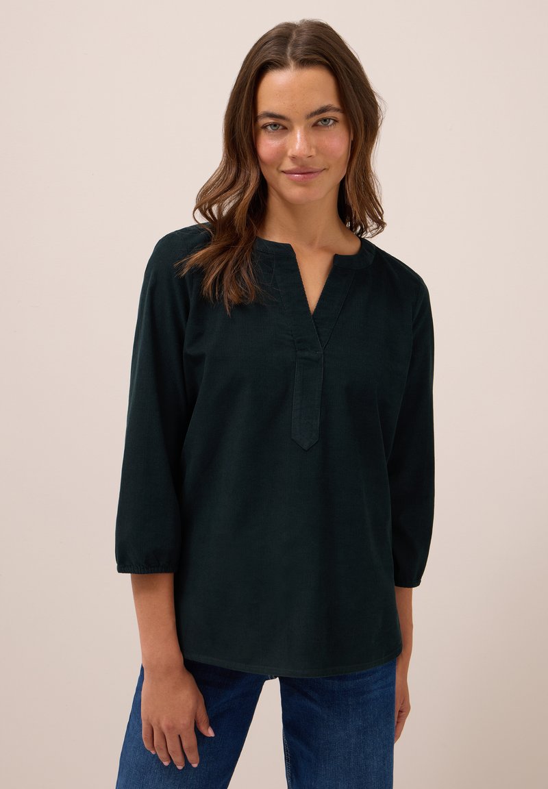 Blusa verde scuro a maniche lunghe con scollo a V, vestibilità comoda e maniche arricciate, realizzata in un tessuto morbido con una superficie liscia.