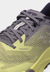 Κίτρινο και γκρι παπούτσι τρεξίματος North Face Enduris 4 με λεπτομερείς κορδόνια και υφασμάτινο επάνω μέρος με υφή.