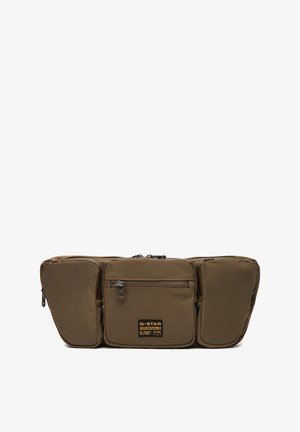 Brązowa torba na pas G-Star Originals z trzema zapinanymi na zamek przegrodami oraz czarno-żółtą naszywką z logo marki na środkowej kieszeni.