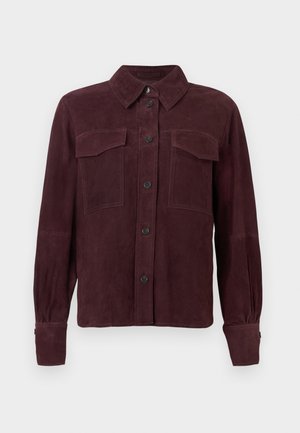Veste en daim bordeaux avec fermeture à boutons, deux poches poitrine et manches longues avec poignets boutonnés. Texture lisse avec un minimum de détails.