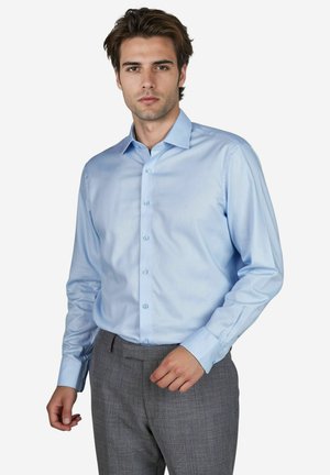 Hellblaues, langärmliges Hemd mit glatter Textur, subtiler Oberflächenbeschaffenheit und abgerundetem Kragen, kombiniert mit grauen karierten Hosen.