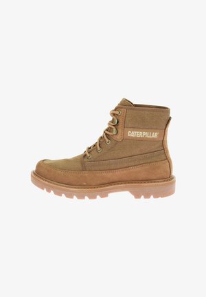 Botín de tobillo marrón con cordones, fabricado en ante y lona, con una suela de goma resistente y un logo de Caterpillar visible en el lateral.