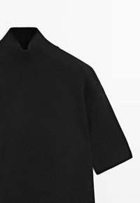 Maglione nero a maglia con colletto alto, maniche corte, texture a coste e una vestibilità ampia. Design semplice senza decorazioni.