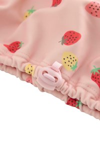 Vaaleanpunainen kangas, jossa on pieniä mansikka- ja keltamarjakuoseja, reunassa on rypytetty reuna ja vaaleanpunainen kiinnitysklipsi varusteena.