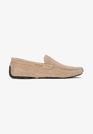 Beige suede slip-on shoes with stitching accents and a black rubber sole. The design features a smooth texture and a rounded toe.