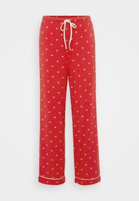Pantalons de pyjama rouges en tissu doux avec un waistband à cordon, ornés d'un motif répétitif de petits nœuds blancs et d'un contraste de bordures blanches au niveau des poignets.