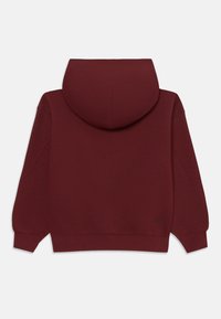 Bordový mikina s dlhými rukávmi, rebrovanými manžetami a spodným okrajom, a čierny logom Nike swoosh v blízkosti pravého dolného rohu.