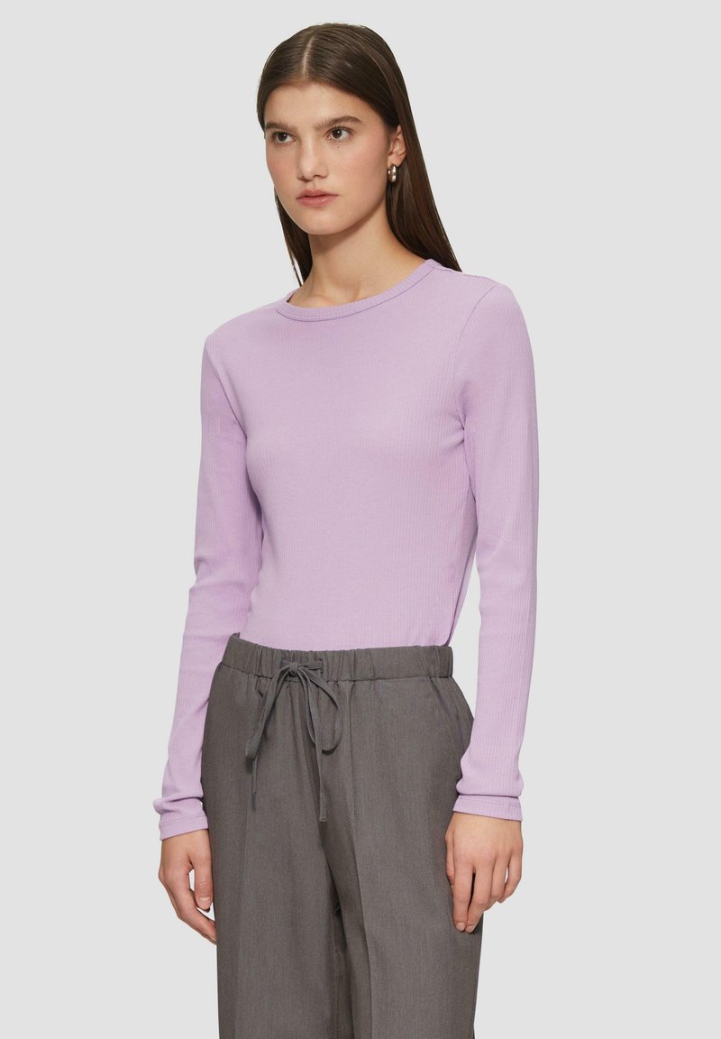 Lichtpaarse geribde lange mouwen top gecombineerd met grijze broek met trekkoord. Slim fit en ronde halslijn met subtiele textuurdetails.