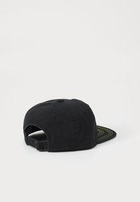 Casquette noire avec une silhouette structurée, dotée d'une visière plate et de coutures vertes sur le dessous. Sangle réglable à l'arrière.
