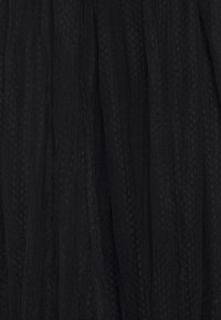 Tissu noir avec un motif discret de petits points et des plis verticaux créant de douces plissures et une texture.