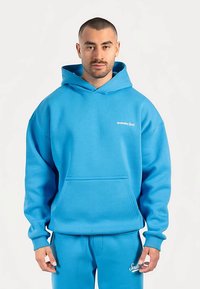 Felpa con cappuccio blu in misto cotone, con tasca frontale, cappuccio con cordoncino e logo ricamato sul petto, abbinata a pantaloni della tuta coordinati.